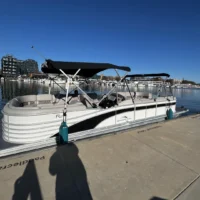 White pontoon boat docked at marina